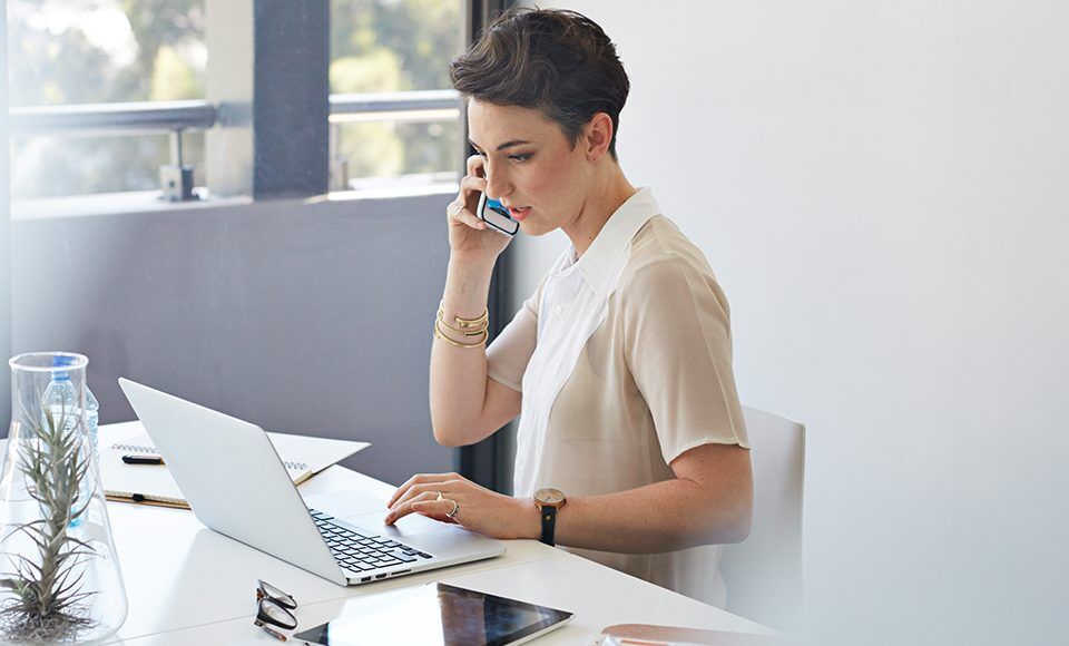 jeune femme au téléphone et sur son ordinateur